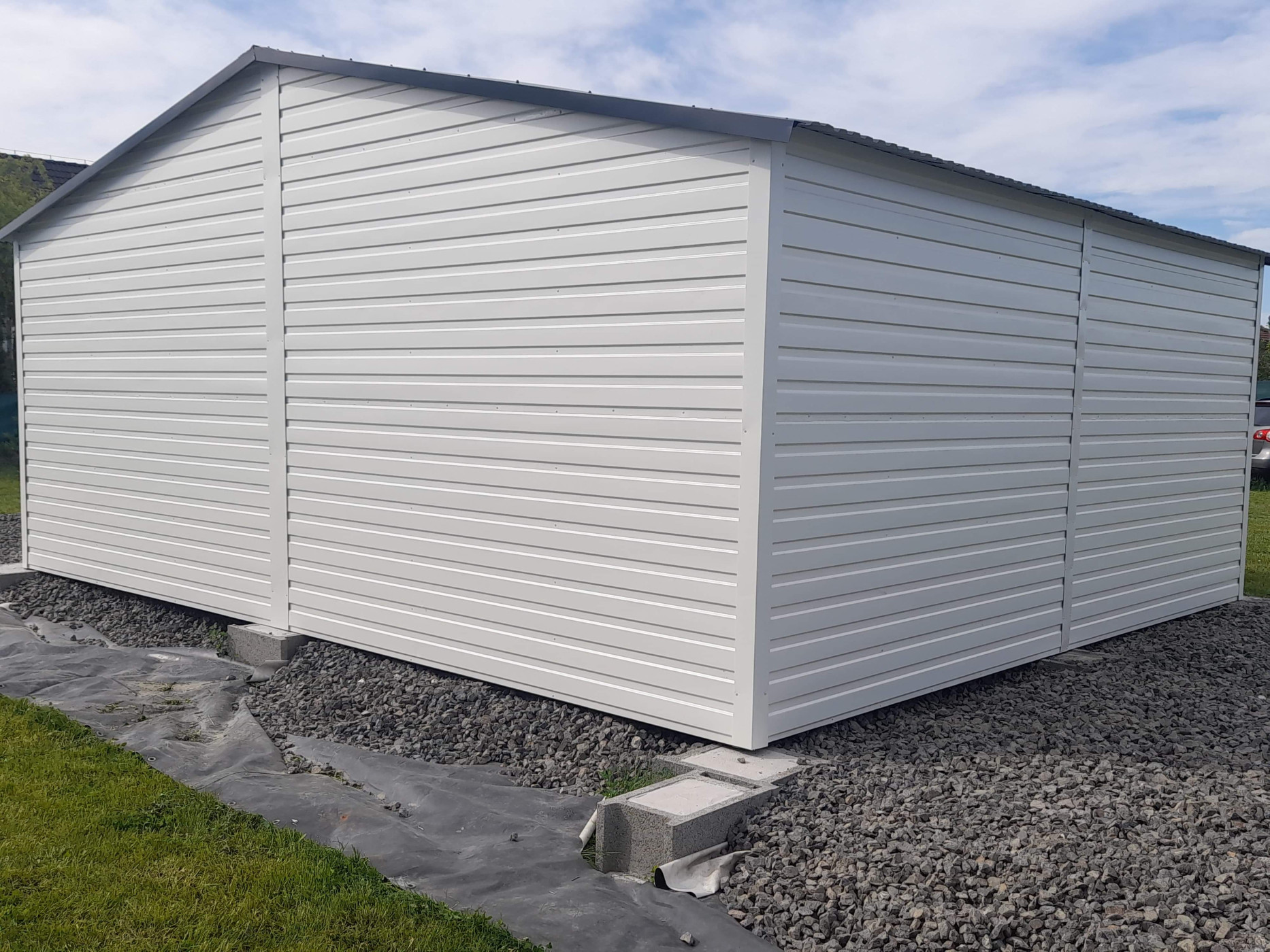 Biela plechová garáž s olištovaním – rohové lišty a lemovanie strechy pre čistý vzhľad.